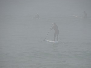 Boardriders at beach in fog